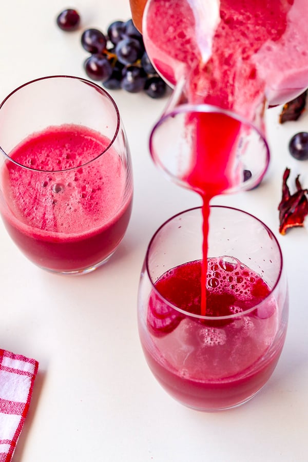pouring fresh grapefruit juice with grapes & hibiscus in a glass