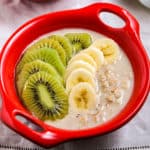 vegan overnight oats with kiwifruit in a small red bowl