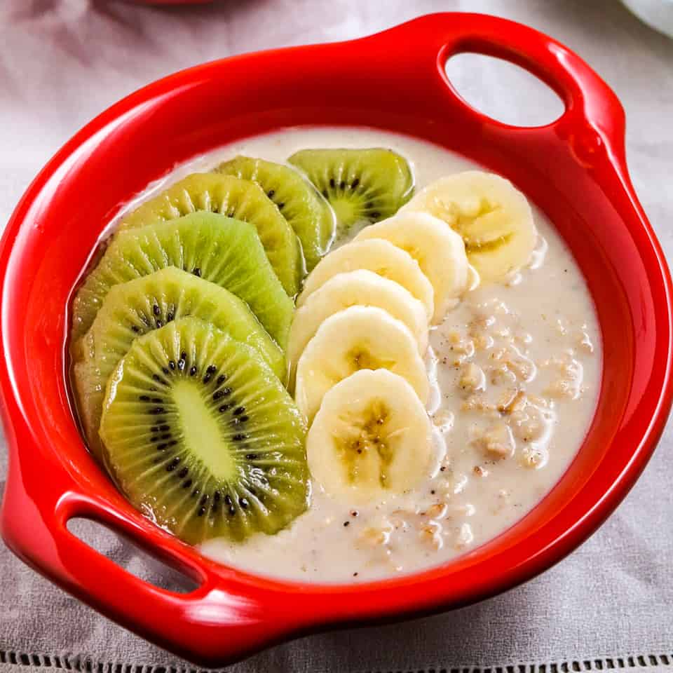 vegan overnight oats with kiwifruit in a red bowl