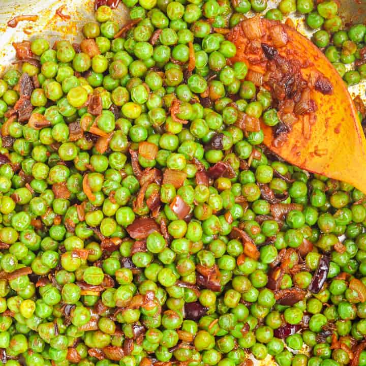 Frozen green peas cooking in onions & spices