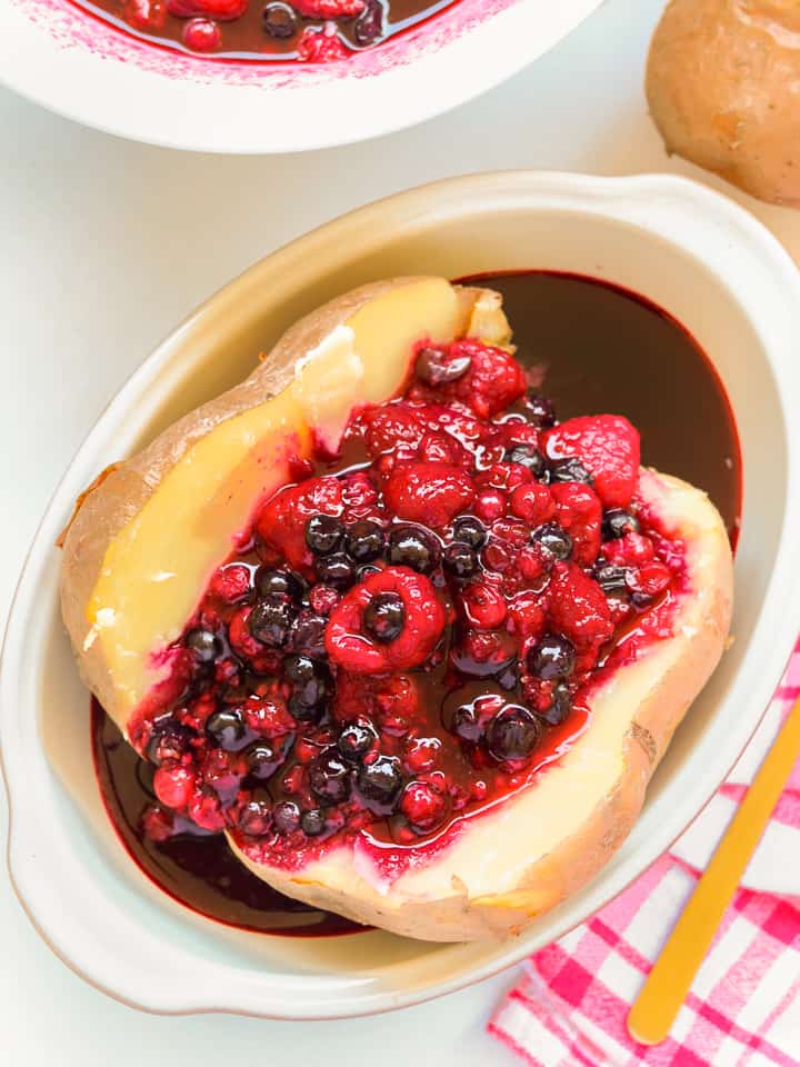 baked potato cut into half with cooked red fruits