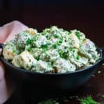 Creamy vegan potato salad garnished with dill & chives